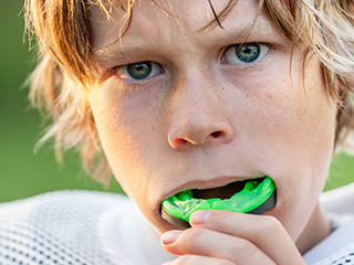 Teen boy putting sportsguard in mouth