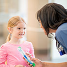 Dental assistant giving child a toothbrush