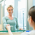 Woman shaking hands with dental team member at front desk