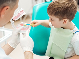 Young boy practicing tooth brushing at dental office
