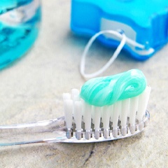 Toothbrush with toothpaste on it next to oral care products