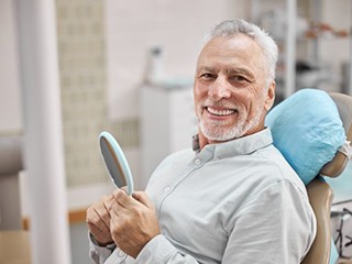 senior man smiling with his new dental implants in Edison 