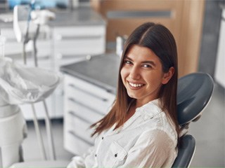 Woman in white collared shirt smiling in dental chair
