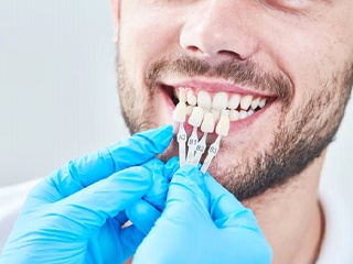 cosmetic dentist in Edison holding a row of veneers in front of a patient’s teeth