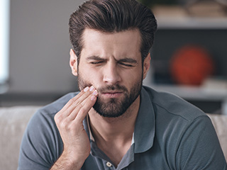 Man holding cheek in pain