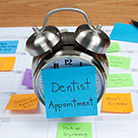 Clock with paper sticky note that says dental appointment