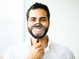 man holding a magnifying glass to his smile 