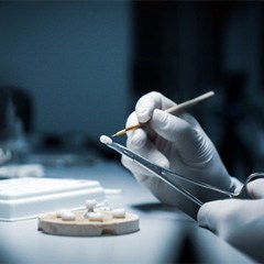 : A lab worker closely processing a dental crown