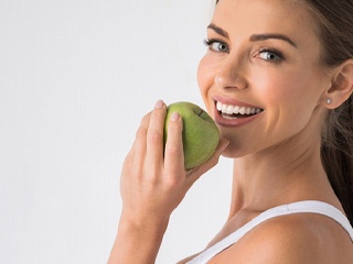 woman biting into a green apple