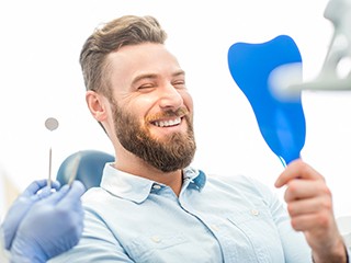 dental patient admiring his new smile in the mirror