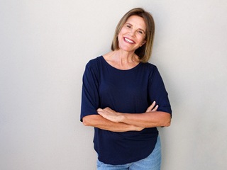 Middle-aged woman in blue shirt smiling with dentures in Edison