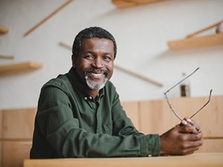 happy elderly man holding his glasses in his hands 