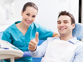 Patient giving thumbs up next to dental assistant after preventing gum disease