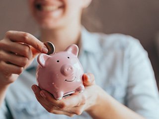 Woman dropping a coin into her piggy bank