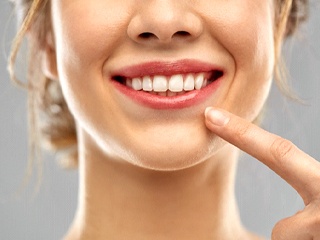 Woman pointing at her dental implants in Edison
