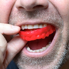 Man placing a custom sportsguard into his mouth.