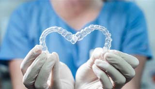 dentist holding Invisalign in Edison in a heart shape