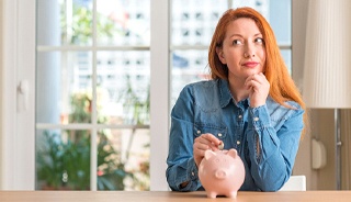 Woman putting coin in piggy bank for Invisalign in Edison