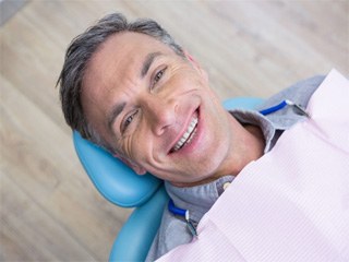 Man in dental treatment chair smiling