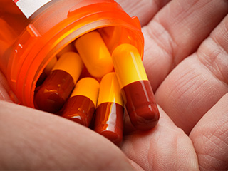 Person pouring antibiotic pills into hand