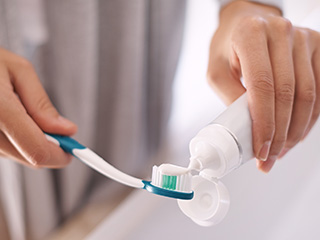 Person putting toothpaste on toothbrush