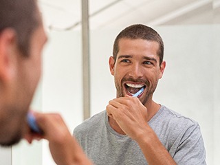  a man brushing to preserve his teeth whitening results
