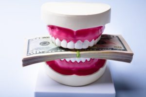 model of teeth biting a stack of money