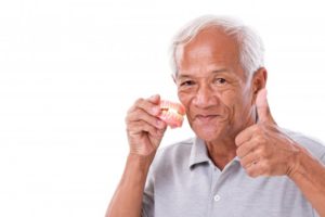 Smiling man holding dentures