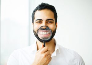 man with magnifying glass in front of smile