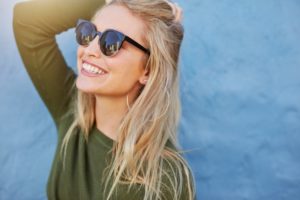 Healthy woman with sunglasses smiles after visiting Edison cosmetic dentist