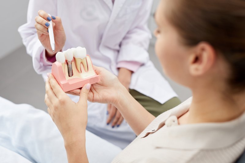 Dentist showing patient model of dental implant