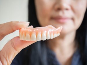 a woman taking her dentures out after a certain amount of time