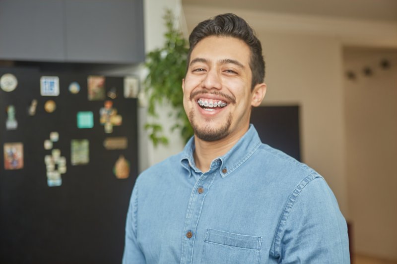 A man smiling with braces over his dental implants