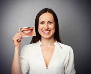 Woman smiling and holding a "before" picture. 