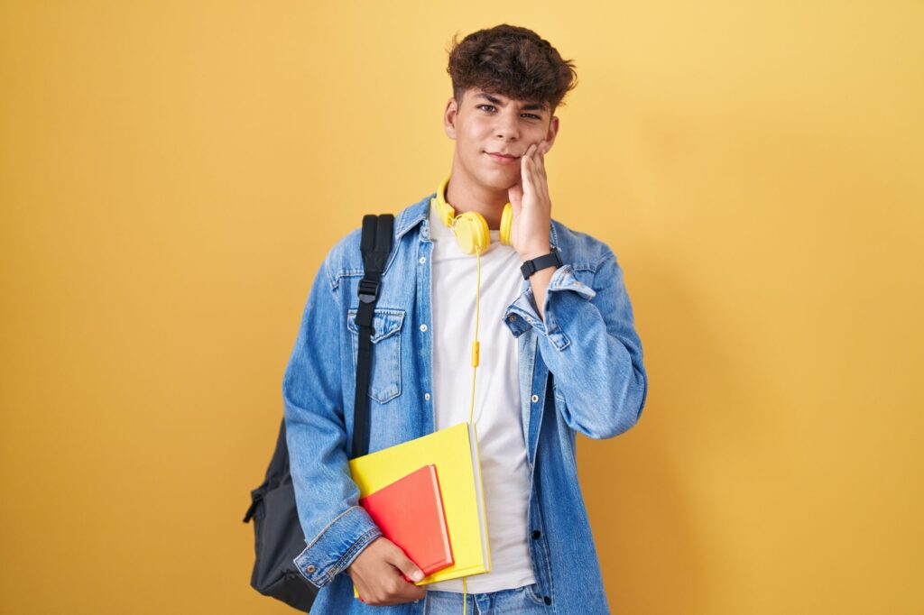 A teenage boy holding his jaw